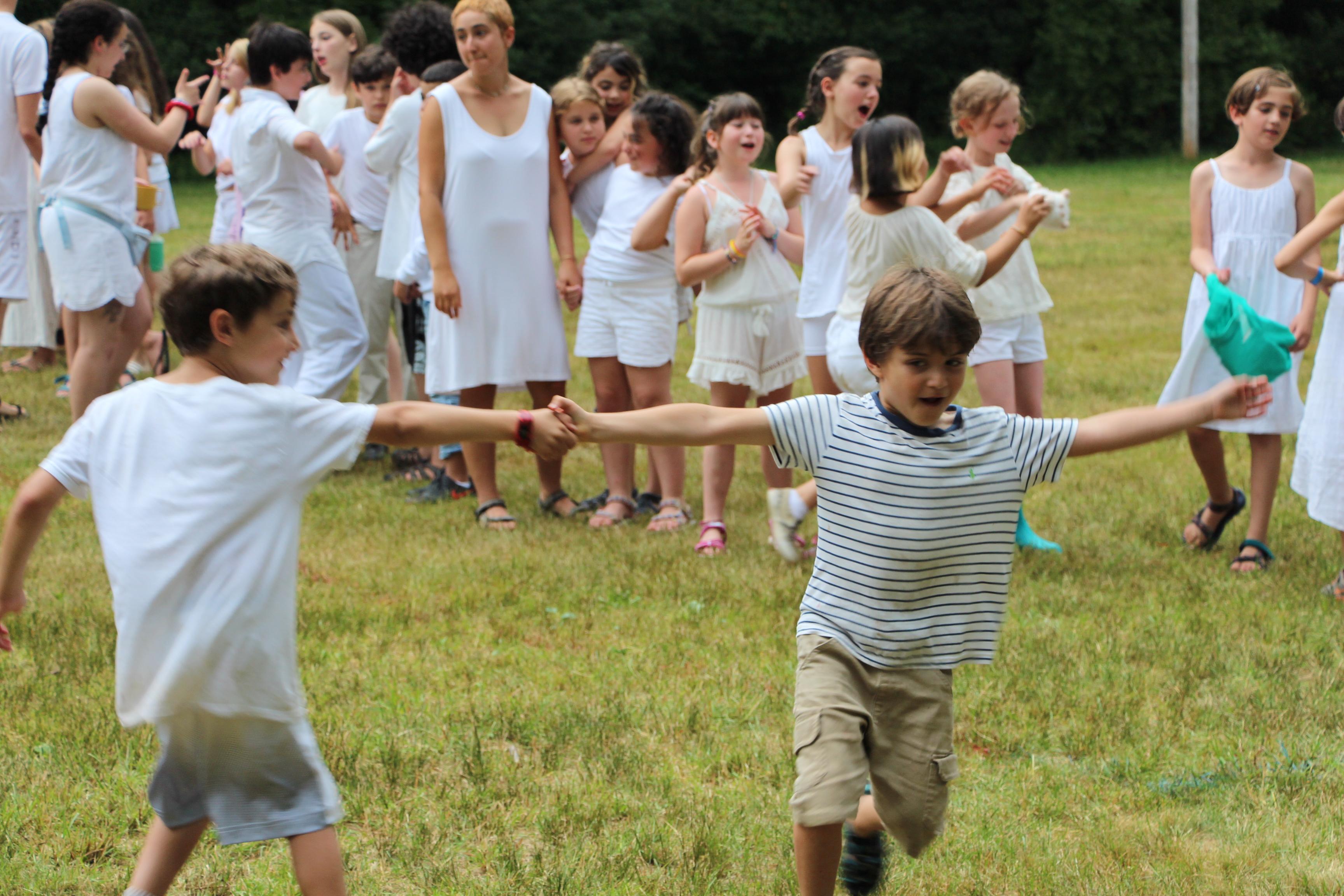 everyone wearing white on Shabbat with two campers swinging in a circle