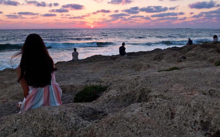 Teens sitting on rocks and watching the sunset in Israel