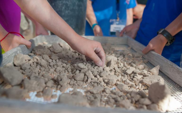 Teens sifting through rocks at an archaeological dig site