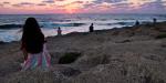 Teens sitting on rocks and watching the sunset in Israel