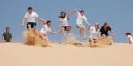 Teens riding down a sand dune in the desert
