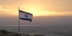 Israeli flag floating in the wind at the top of Masada during sunrise